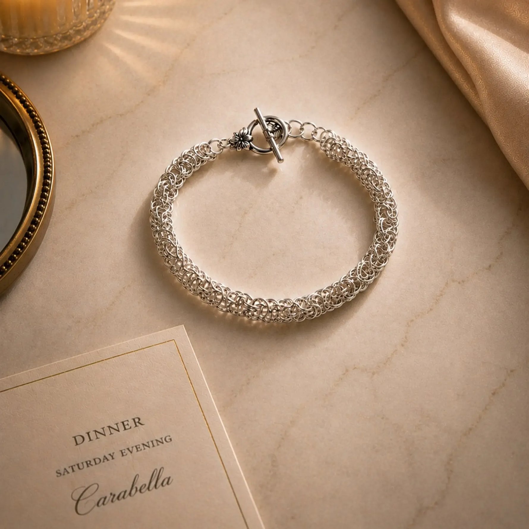 Zoe sterling silver Byzantine weave bracelet styled for an elegant evening on a marble surface with candlelight and refined accessories.