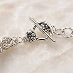 Macro photograph of the floral sterling silver toggle clasp on the Zoe Byzantine weave bracelet.