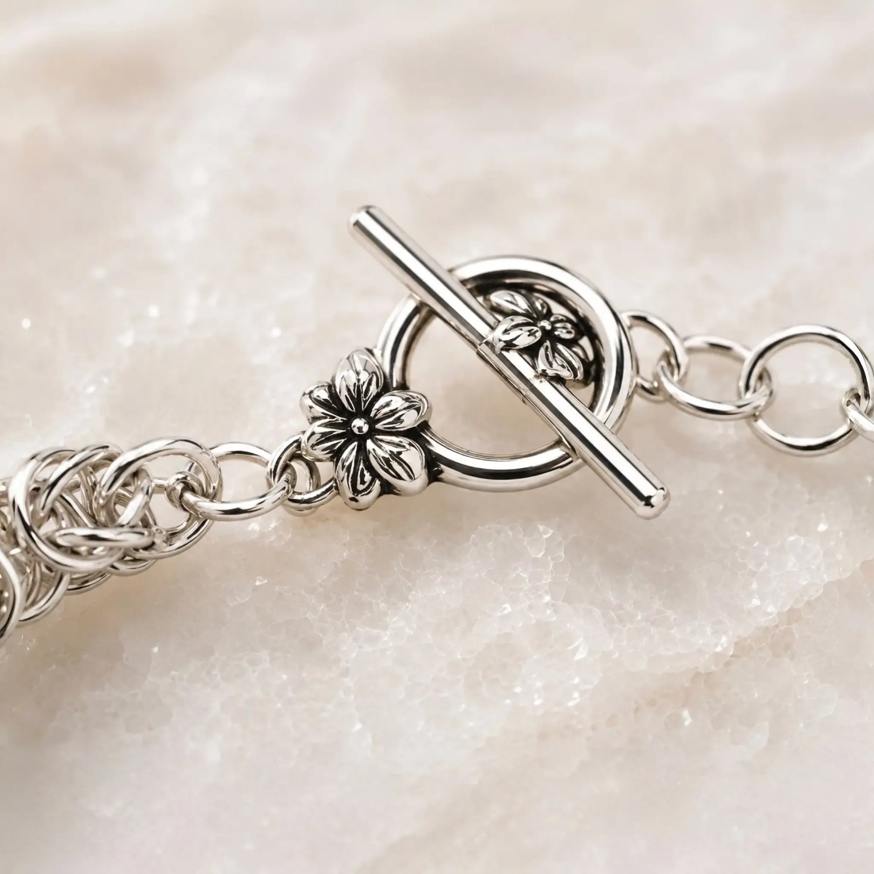 Macro photograph of the floral sterling silver toggle clasp on the Zoe Byzantine weave bracelet.