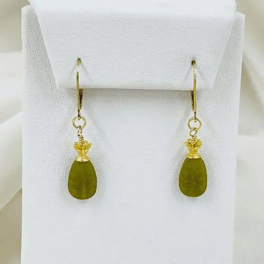 Layla Carved Jade Earrings displayed on a white jewelry stand, highlighting the sculpted jade drops and polished 14k gold detailing.