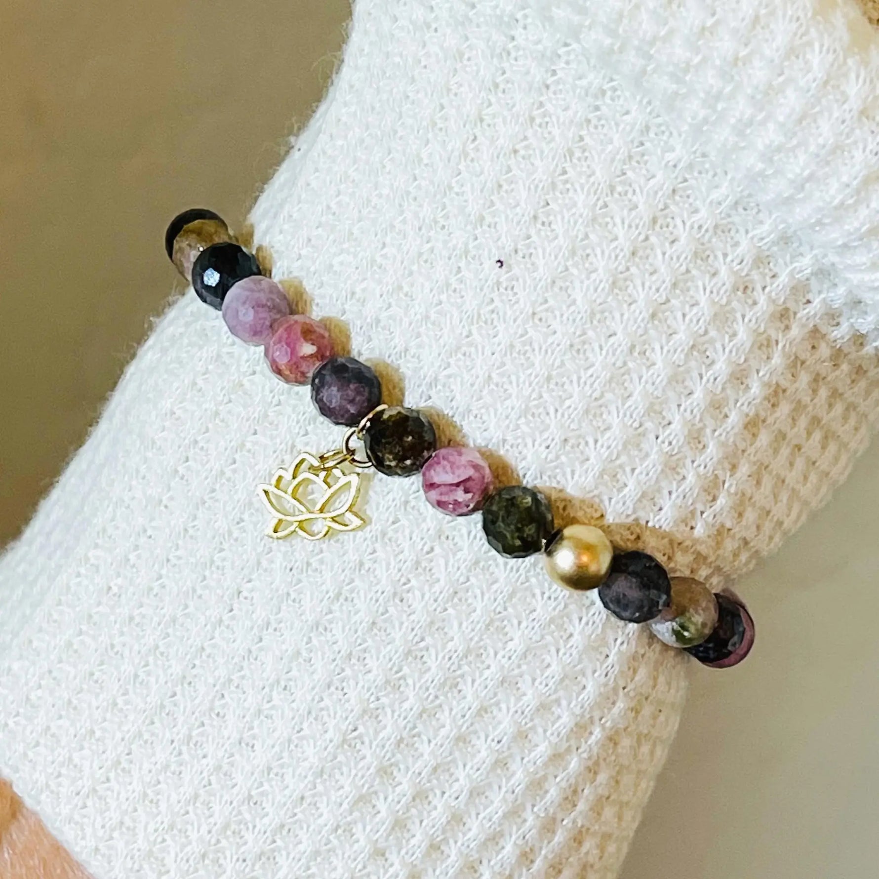 Close up of the Layla Gemstone Bracelet worn on the wrist, highlighting rainbow tourmaline gemstones, gold accents, and the delicate lotus charm.