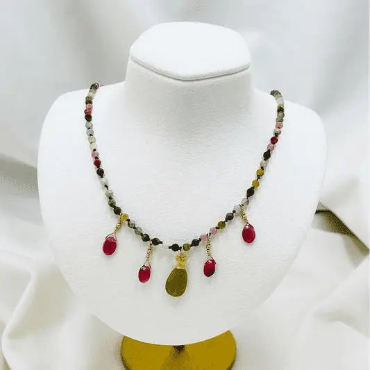 Layla Gemstone Necklace displayed on a jewelry bust, highlighting the tourmaline strand, ruby drop accents, and carved jade leaf focal pendant.