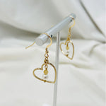 Close-up of Harlow gold earrings featuring luminous pearl and honey opal gemstone