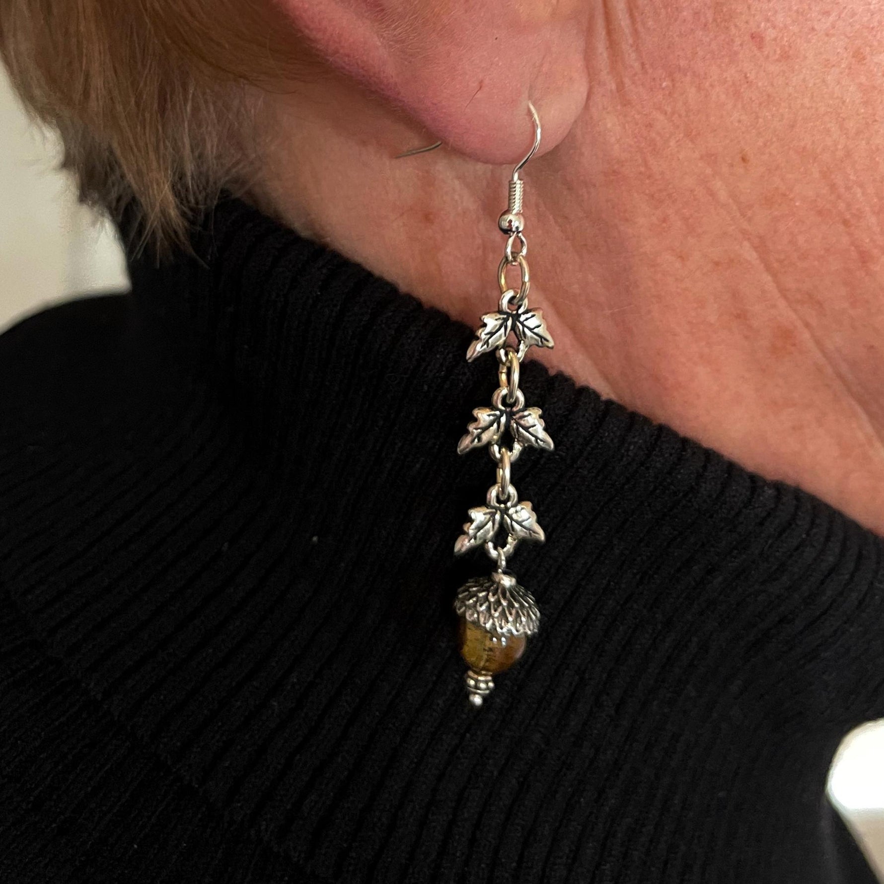 Tiger’s Eye sterling silver drop earrings worn close to the ear, revealing their graceful length, natural gemstone warmth, and softly sculpted botanical accents.